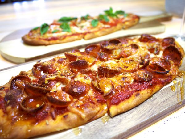 A sizzling pepperoni and cheese pizza on a wooden board, topped with melted cheese and crispy pepperoni slices, served hot.