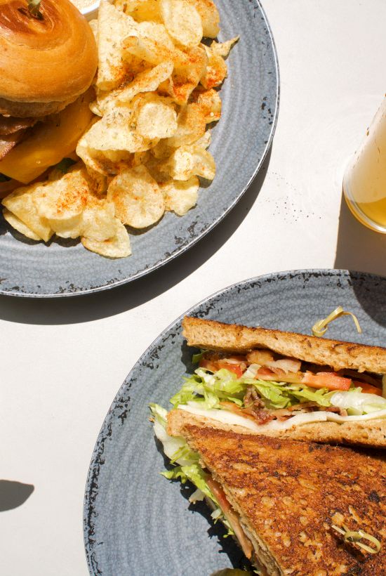 A spread of sandwiches with chips and a couple of drinks set on the table.