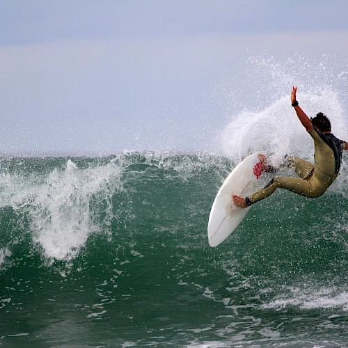 A surfer executes an arcing turn on a hollow green wave, spray flying as they ride a white shortboard. End.